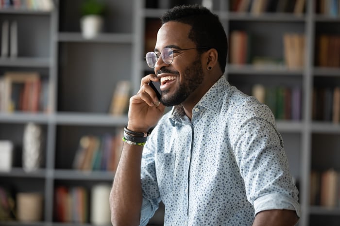 An investor smiles while talking on the phone. 