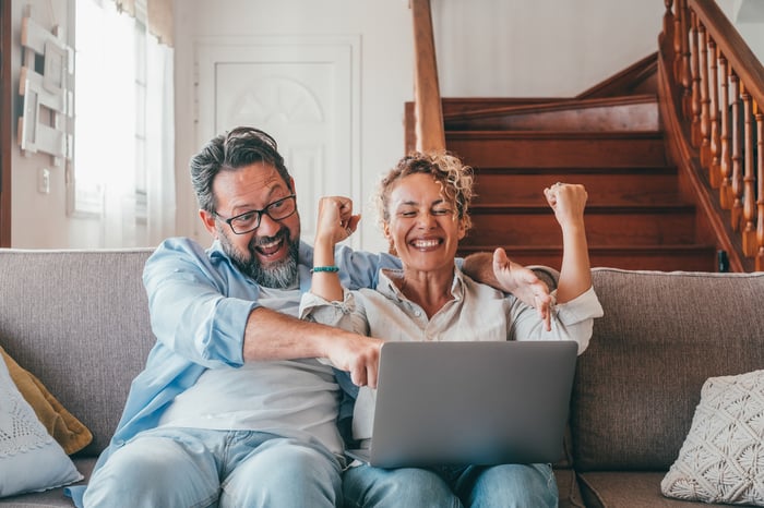 Investors celebrate, looking at laptop.