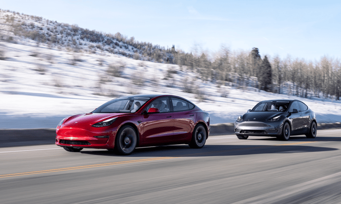 Two Teslas driving on a road.