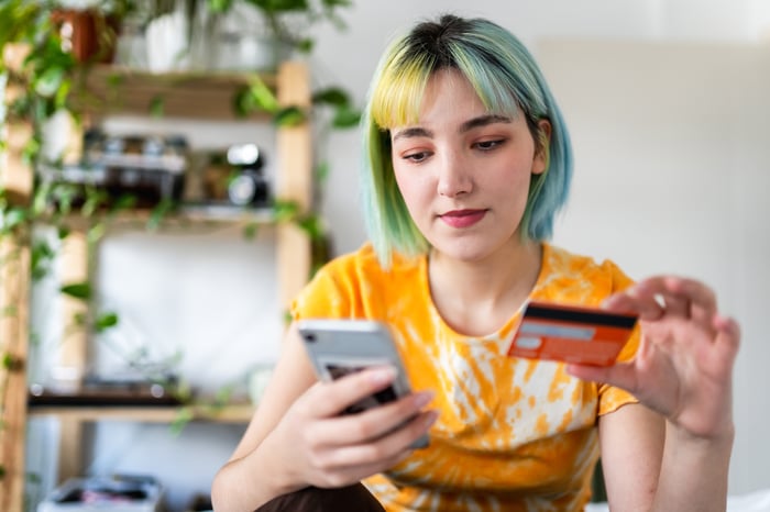 A person holding a credit card to make a purchase on their iPhone.