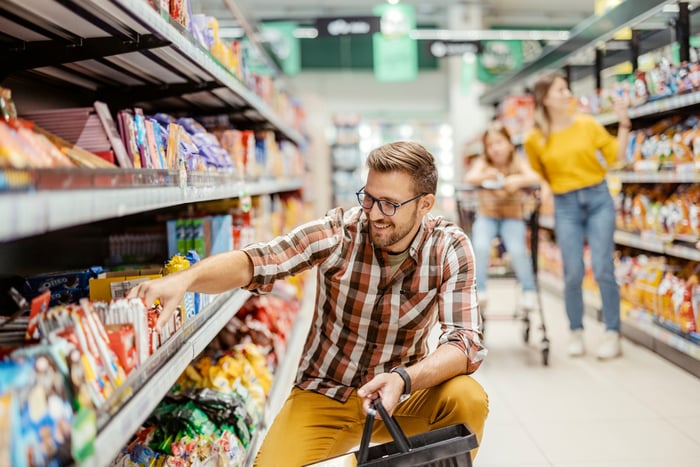 A smiling shopper in a grocery store aisle.