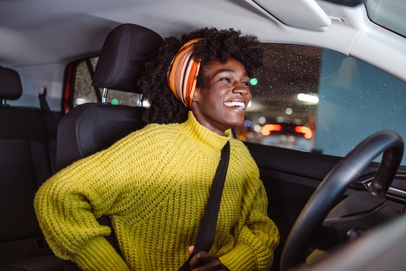 A person buckles their seat belt in a car.