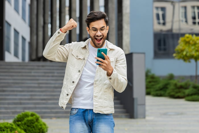A person looking at a smartphone celebrates.