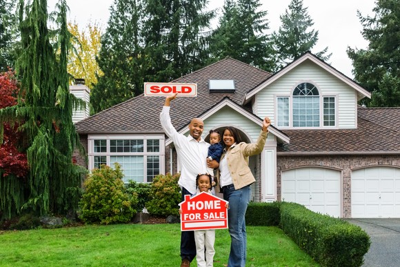 Family standing in front of a sold house.