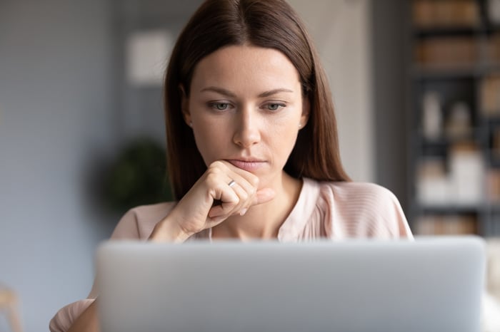 Person working at desk and looking at laptop.
