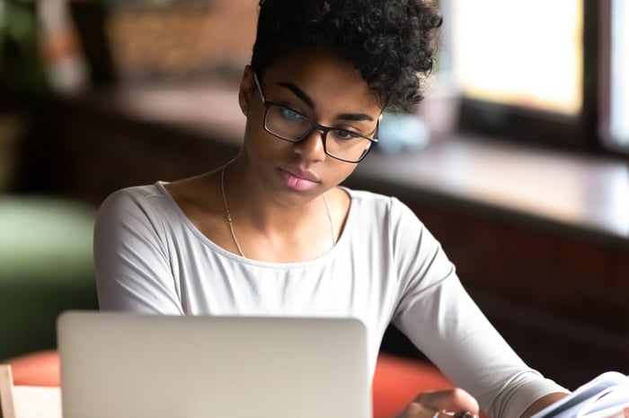 A person looks thoughtfully at a computer.
