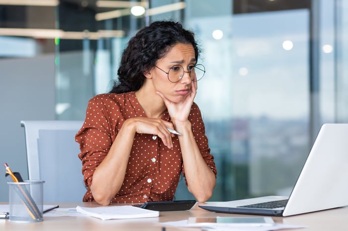 A person in an office looks at a computer with a concerned face.