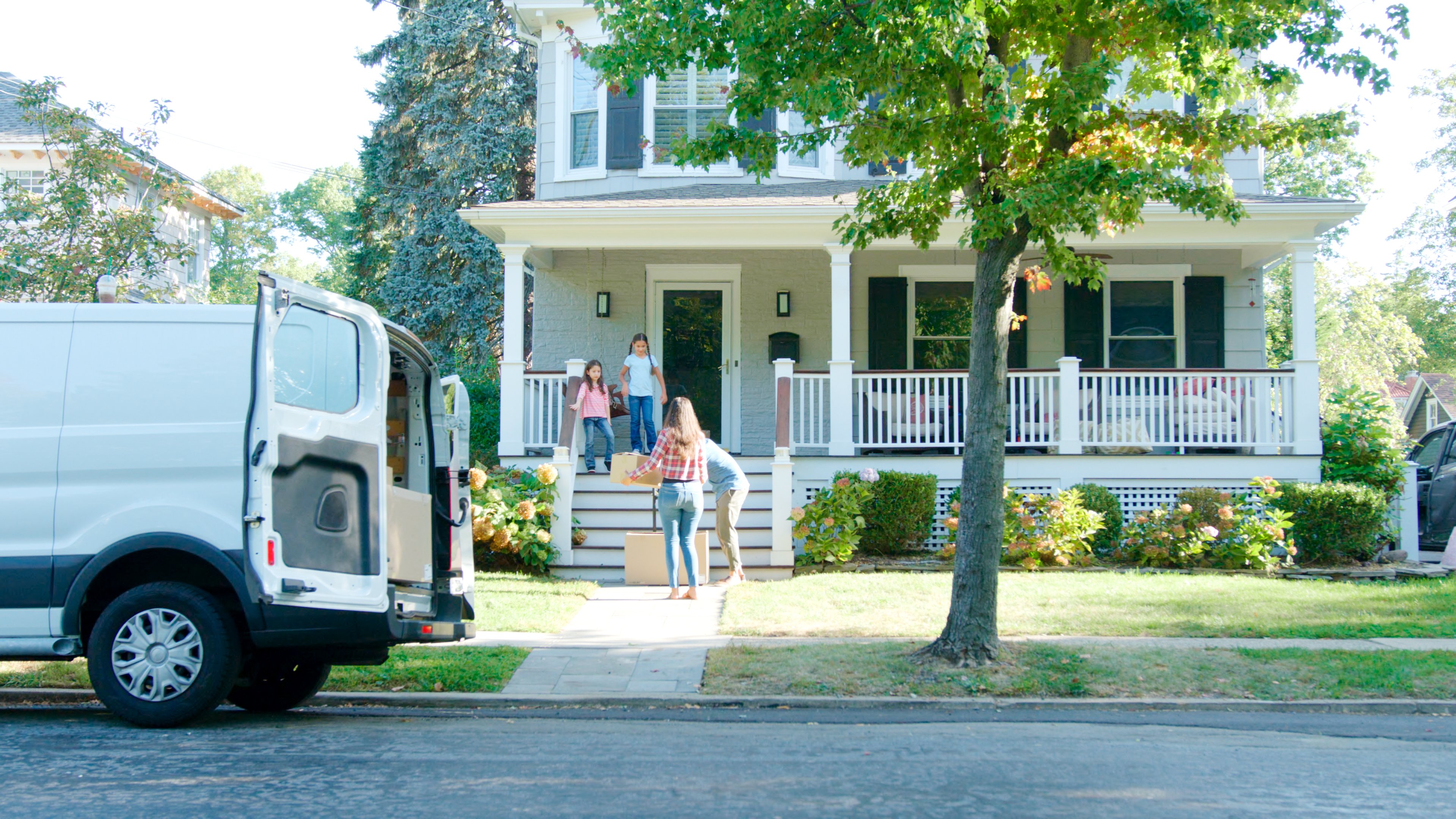 Family walking into a home with a van parked in front. 