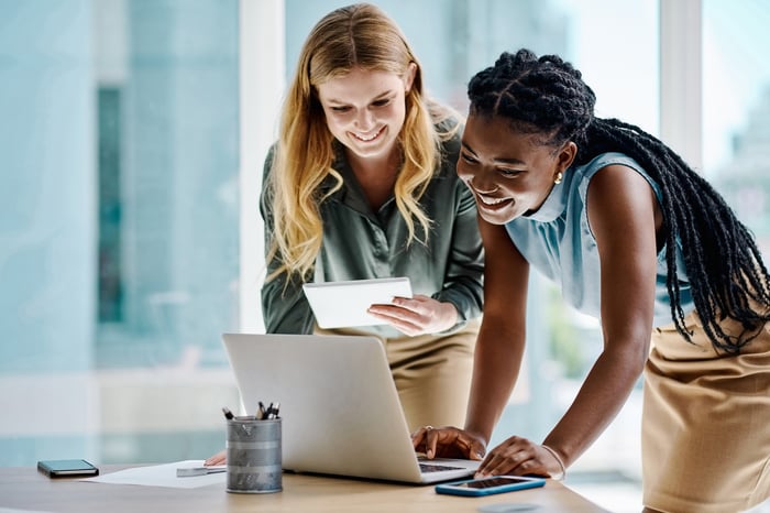 Two investors smile while studying something on a computer in an office.