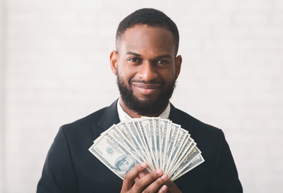 A person holding a fan of $100 bills.