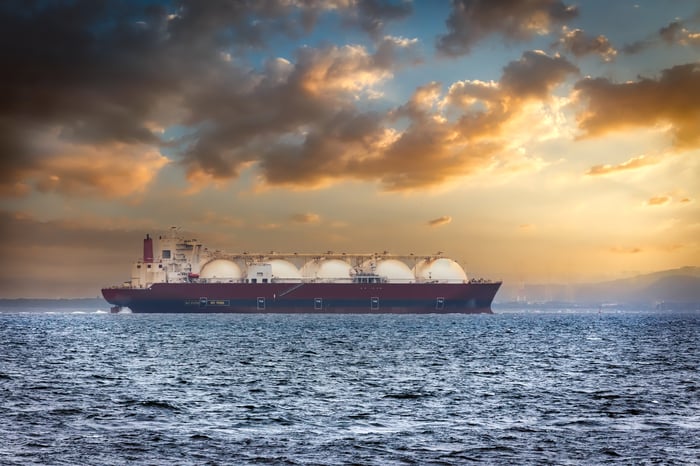 An LNG tanker silhouetted against a sunset sky.