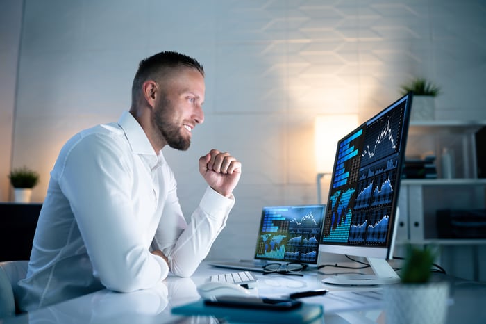 A person smiling and looking at a computer monitor.