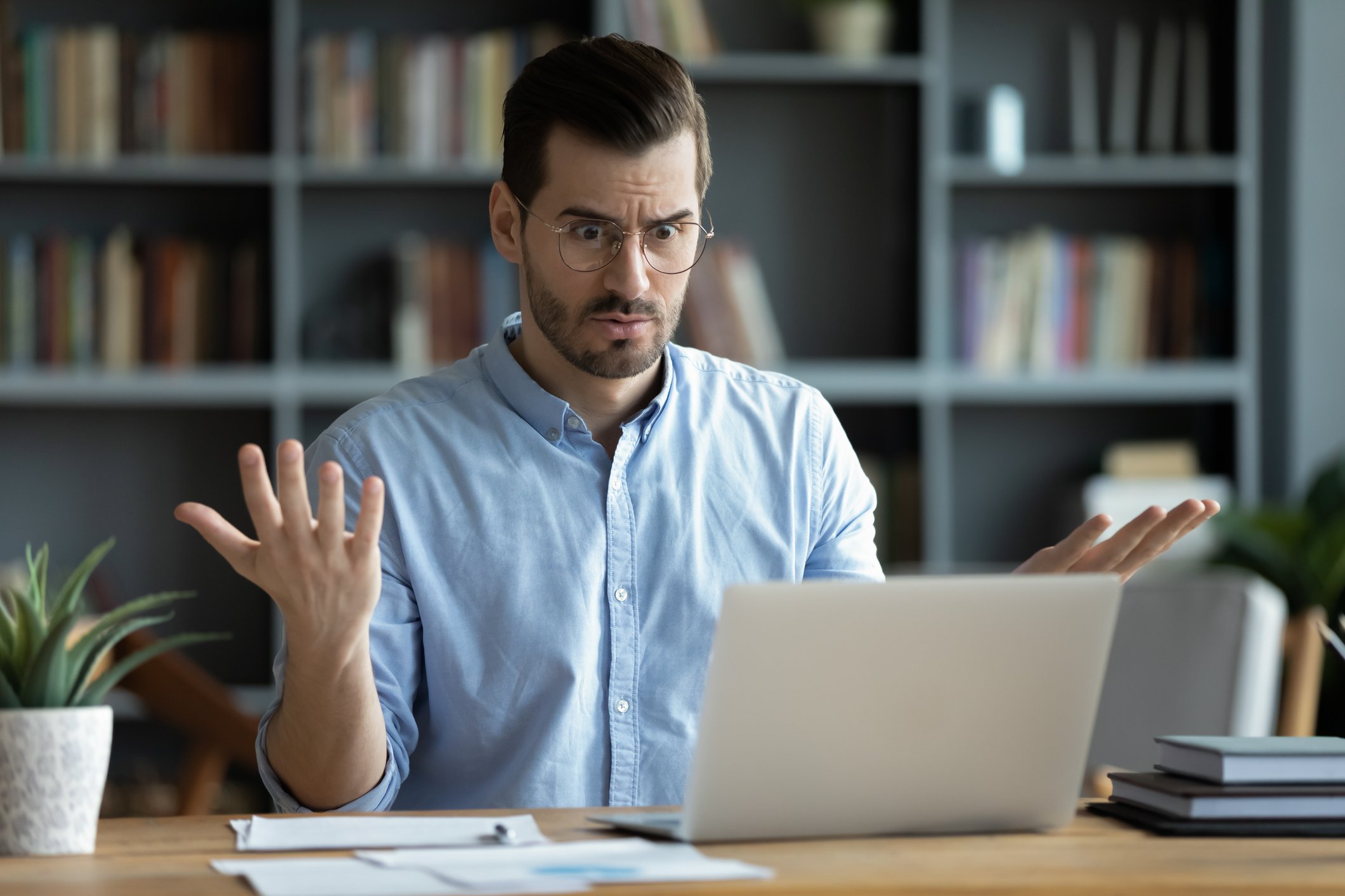 Man looking at a laptop with a confused expression.