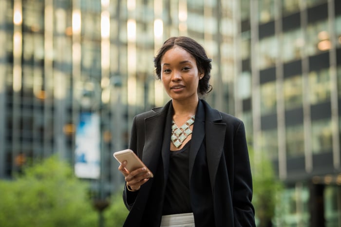 Person in suit standing outside, holding phone.