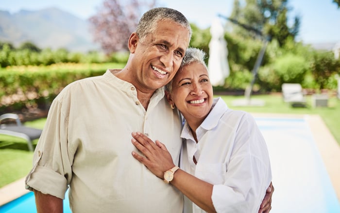 Two people hugging in front of a swimming pool.