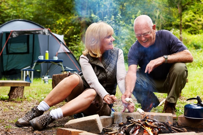 Smiling people sitting around campfire.
