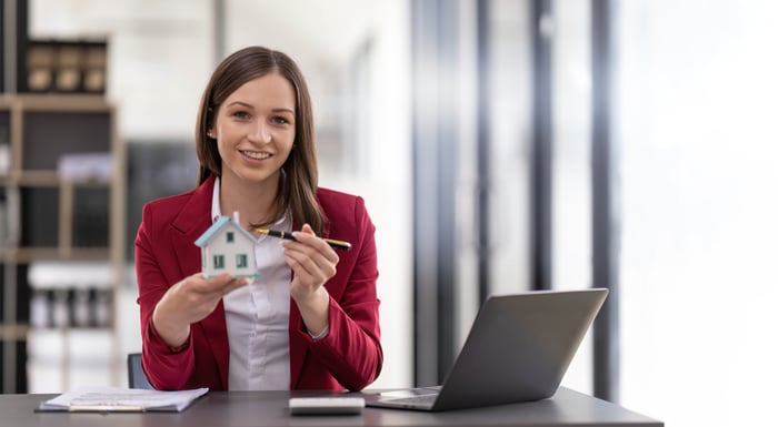 A person points to a model home in front of a laptop.