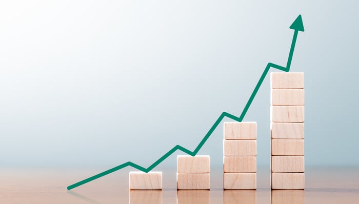 An upward-trending green arrow bouncing up blocks stacked in ascending columns.