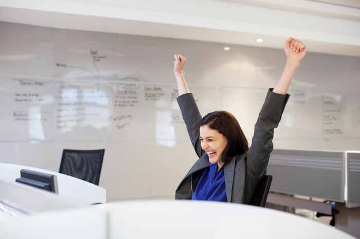 Person looking at their computer screen, celebrating.