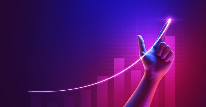 A hand pointing at a line going up over a bar chart.