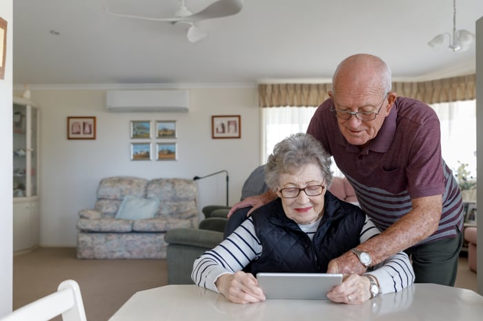 Two people looking at tablet at table.