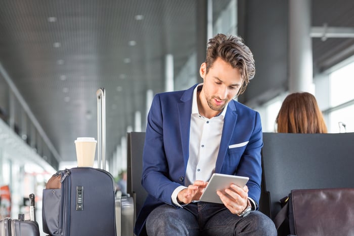 Person sitting at airport gate, using a tablet.