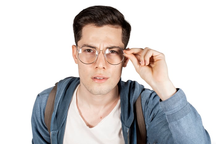 Person squinting at something through glasses.