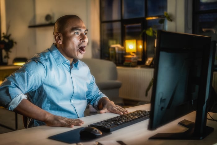 A person looking shocked while staring at a computer screen. 
