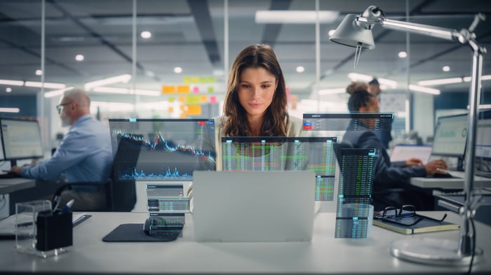 A person in an office looks at several different data screens.