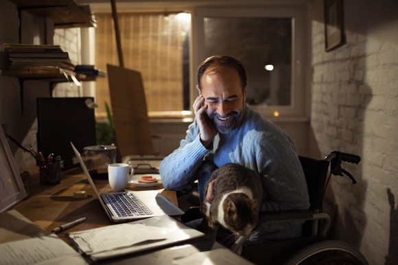 Person talking on their cellphone with a cat in their lap.