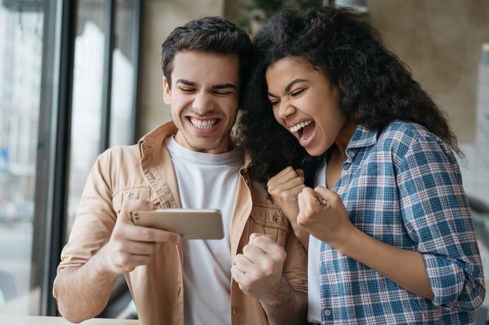 Two people celebrate what they see on a shared smartphone.
