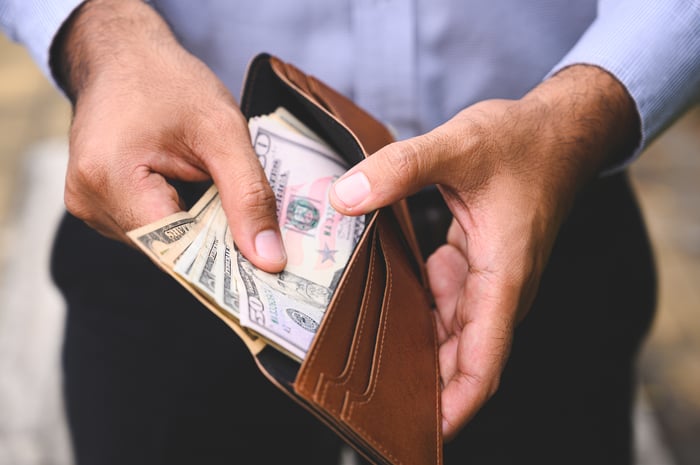 Person looking through cash in a wallet. 