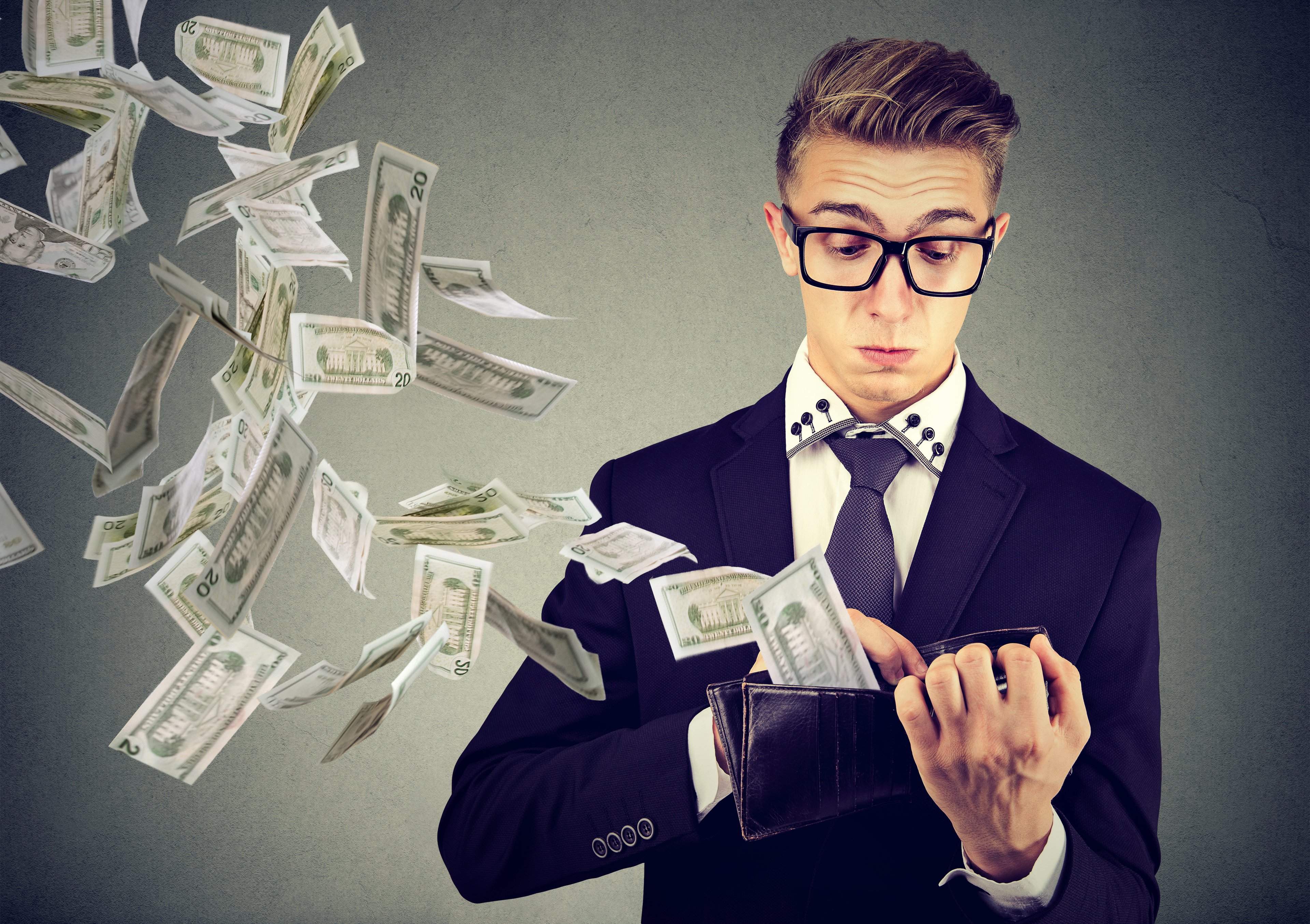 Person in suit, throwing cash out of a wallet.