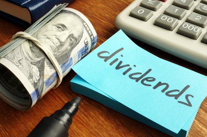 Money next to sticky note with word dividend written on it. 