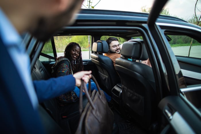 Passenger getting into the backseat of a ride-hailing vehicle.
