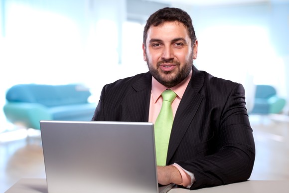 Someone sitting at a table and using a laptop.