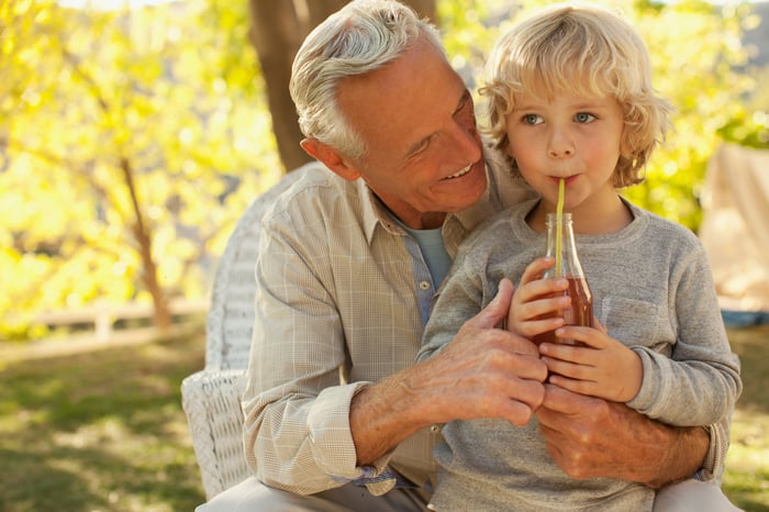 An adult and a child with a bottle of cola.