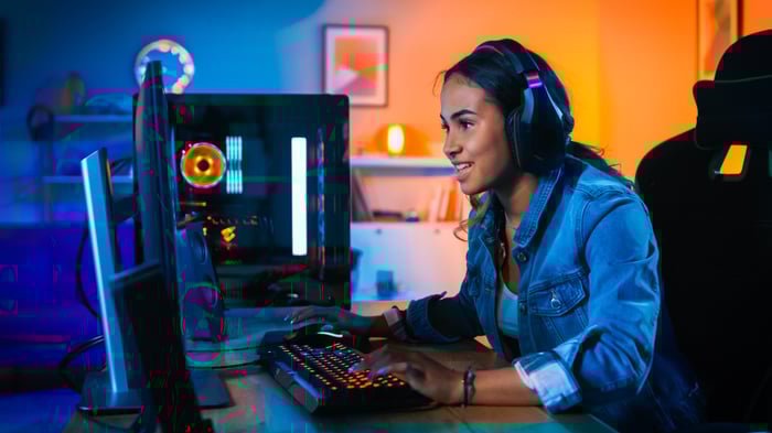 Person wearing headphones and sitting in front of a gaming computer.