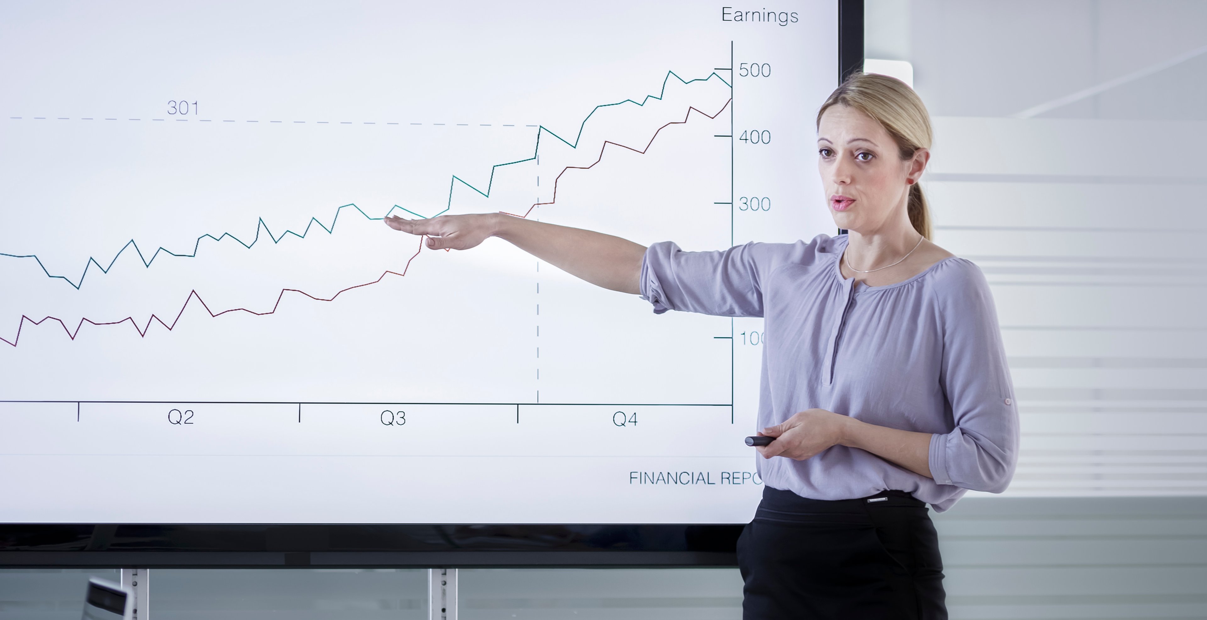 A person pointing to a stock chart projected on a screen.