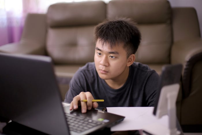 A person looking at a laptop and using the mouse pad.