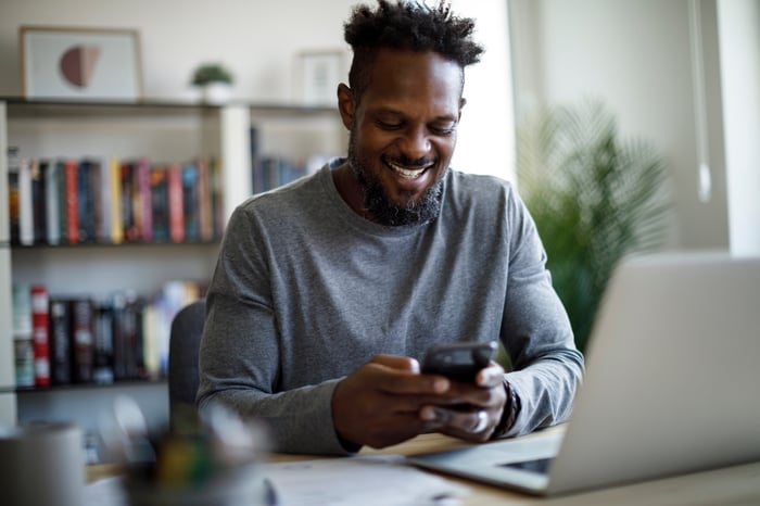 A person looking at a phone and smiling.