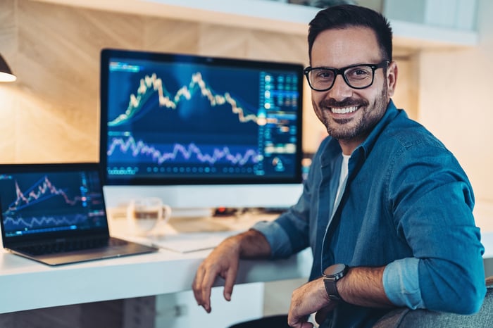 Happy investor with financial charts working from home.