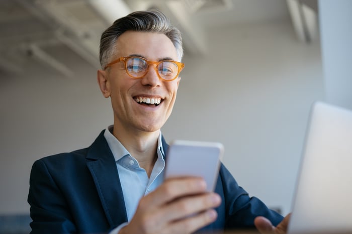 A person smiles at a smartphone.