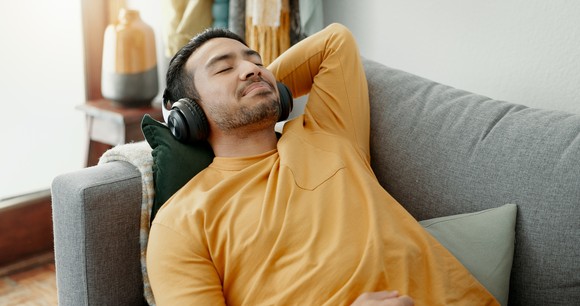 A person relaxing on a couch with headphones on.
