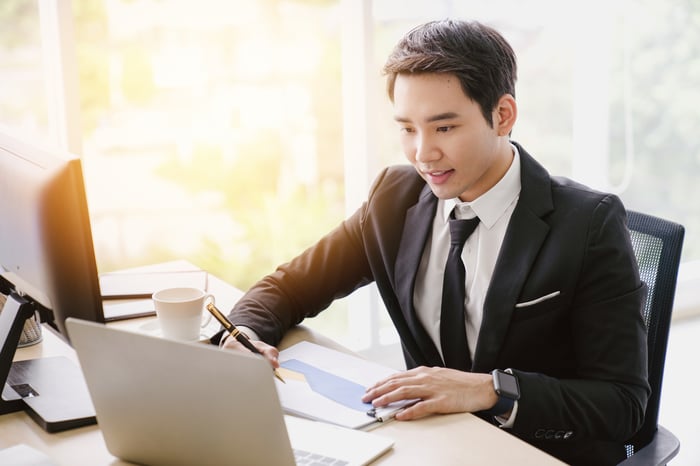Businessman with a chart looking at his computer.