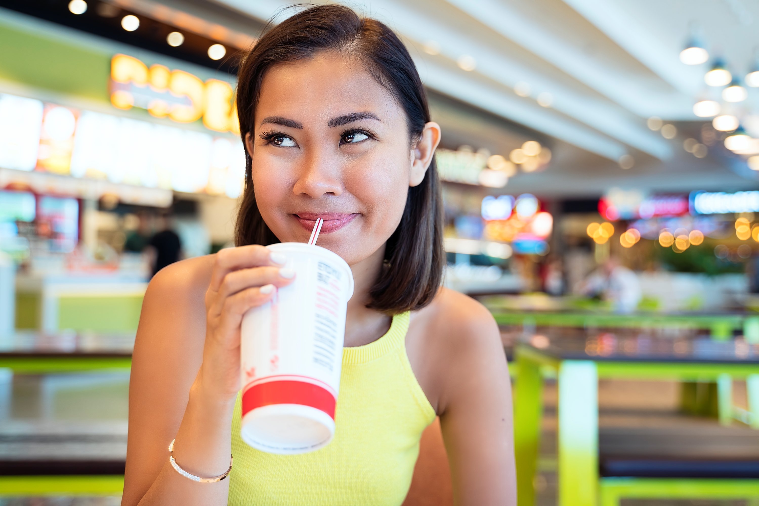 Person drinking at a food court.