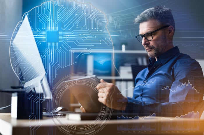 A person looking at a laptop with a digital image of a circuit diagram inside a human head in the background.