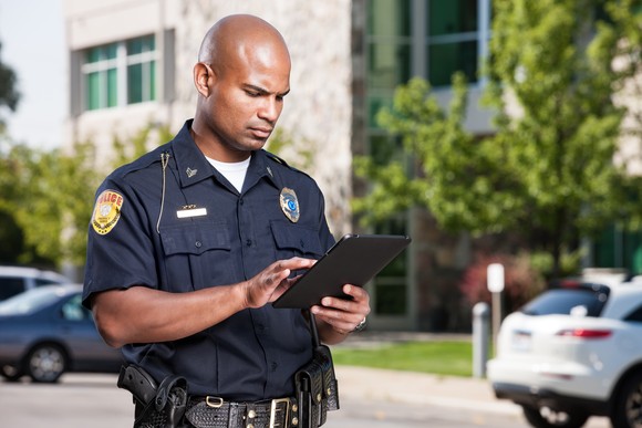 A law enforcement officer does work on a tablet device.