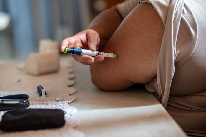 Close-up of a person injecting themself in the arm. 