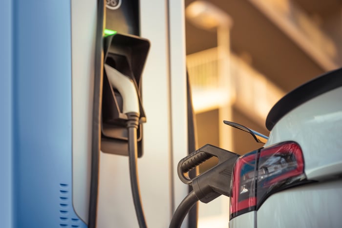 An electric car plugged into a charger at a charging at a station.
